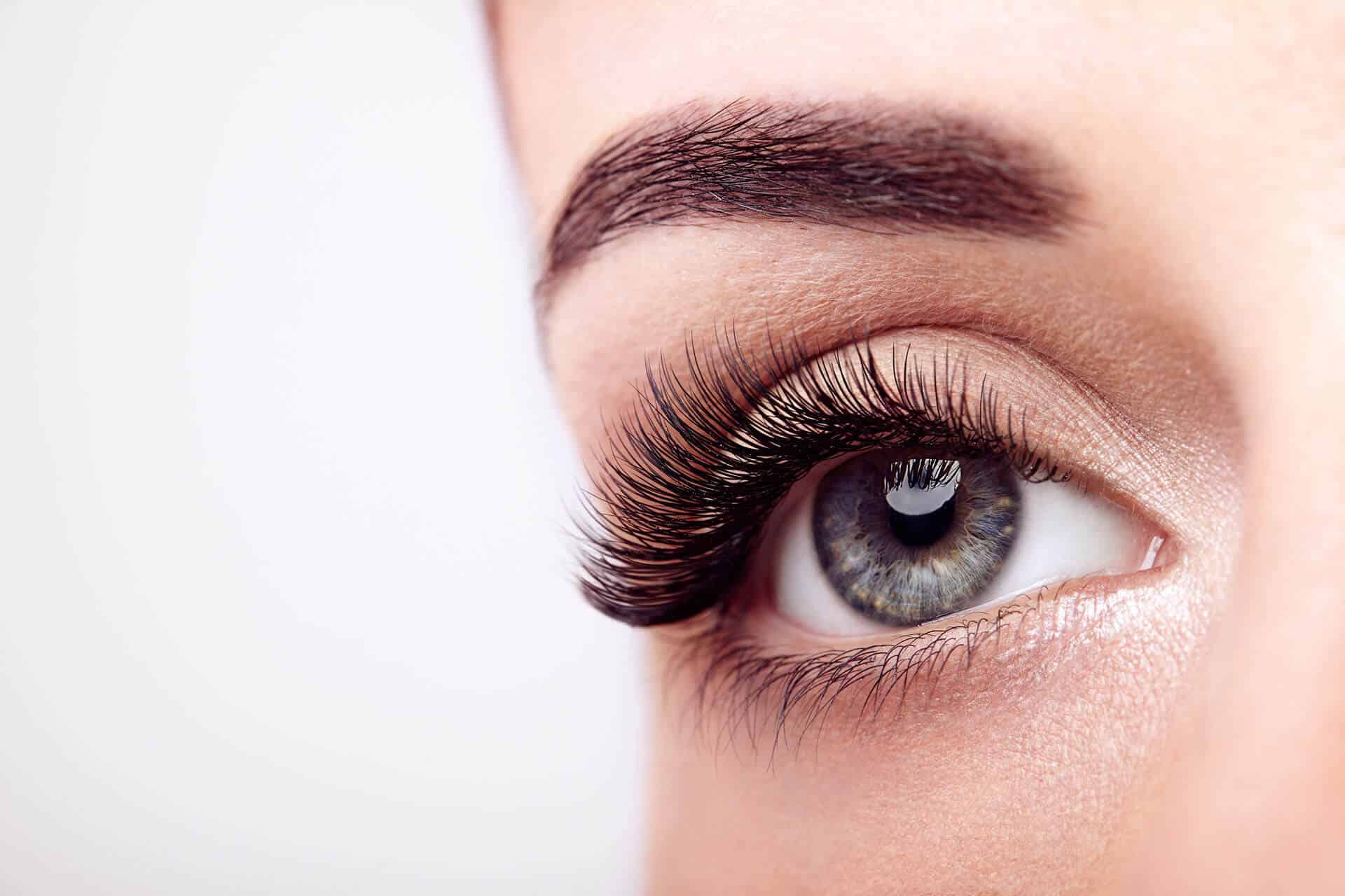 Close-up of a woman’s eye with long false eyelashes showing the upper lash line and eyebrow