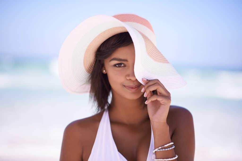 woman at the beach wearing a hat and smiling